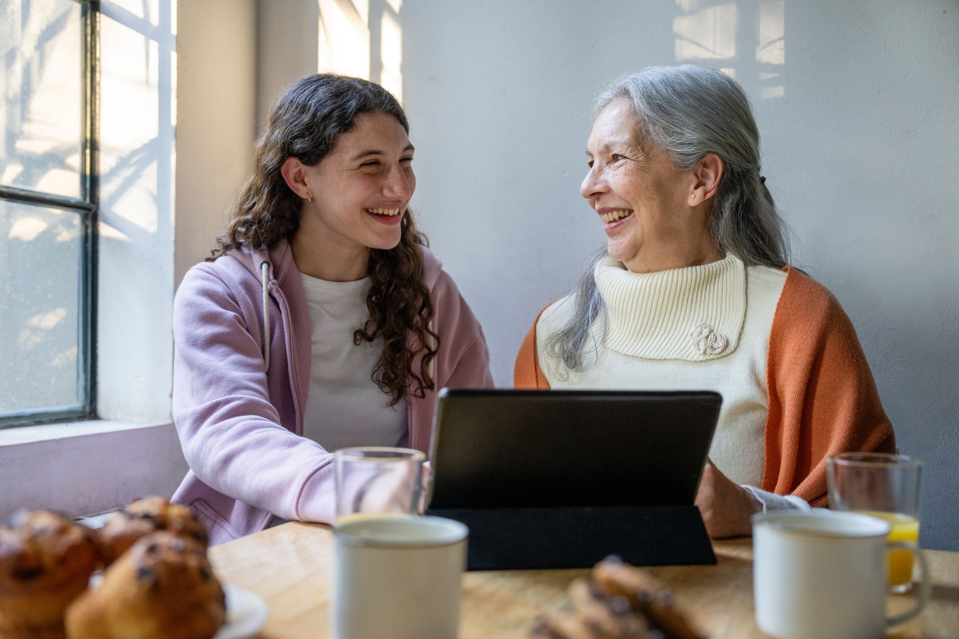 Cheerful young girl helping her grandmother with her holiday shopping online